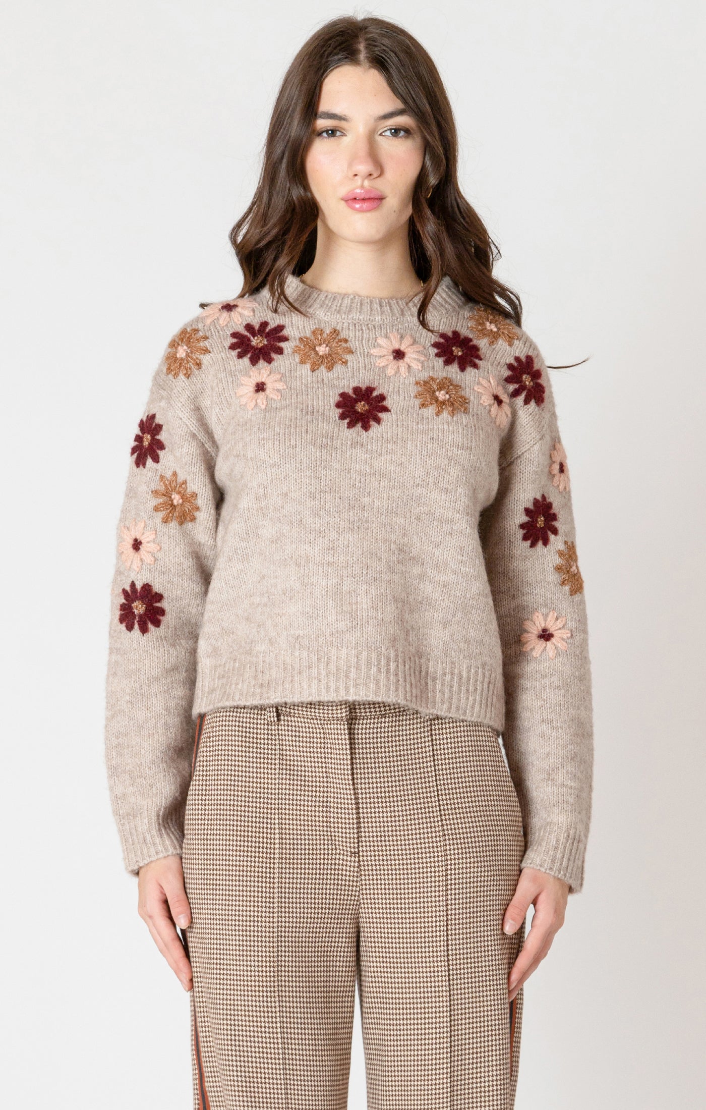 A cozy oat colored knit sweater with fall colored flowers stitched into the arms and upper bodice.