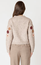 A cozy oat colored knit sweater with fall colored flowers stitched into the arms and upper bodice.