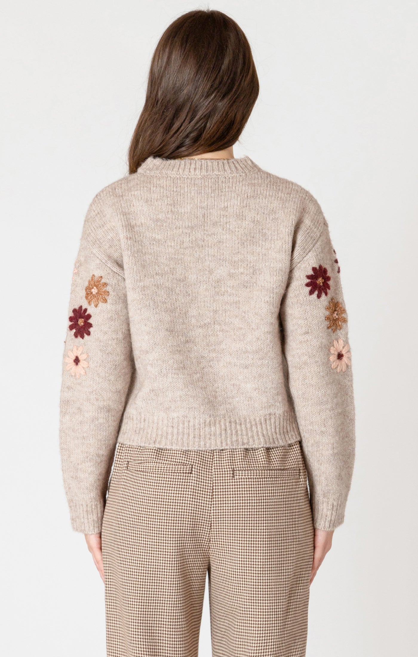 A cozy oat colored knit sweater with fall colored flowers stitched into the arms and upper bodice.
