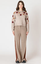 A cozy oat colored knit sweater with fall colored flowers stitched into the arms and upper bodice.