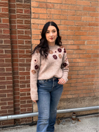 A cozy oat colored knit sweater with fall colored flowers stitched into the arms and upper bodice.