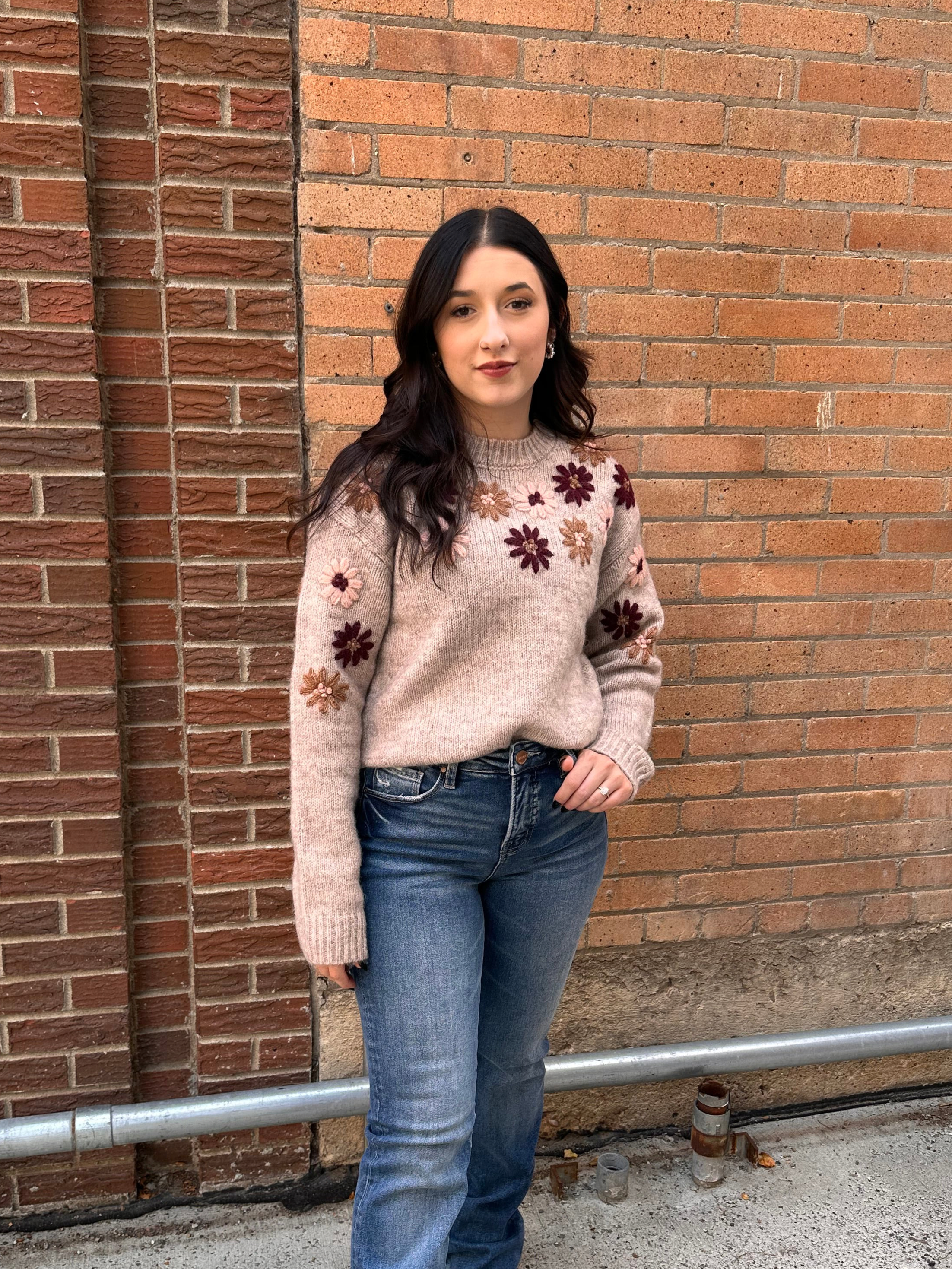 A cozy oat colored knit sweater with fall colored flowers stitched into the arms and upper bodice.