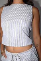 Person wearing a sleeveless white and blue striped top with matching pants against a neutral background
