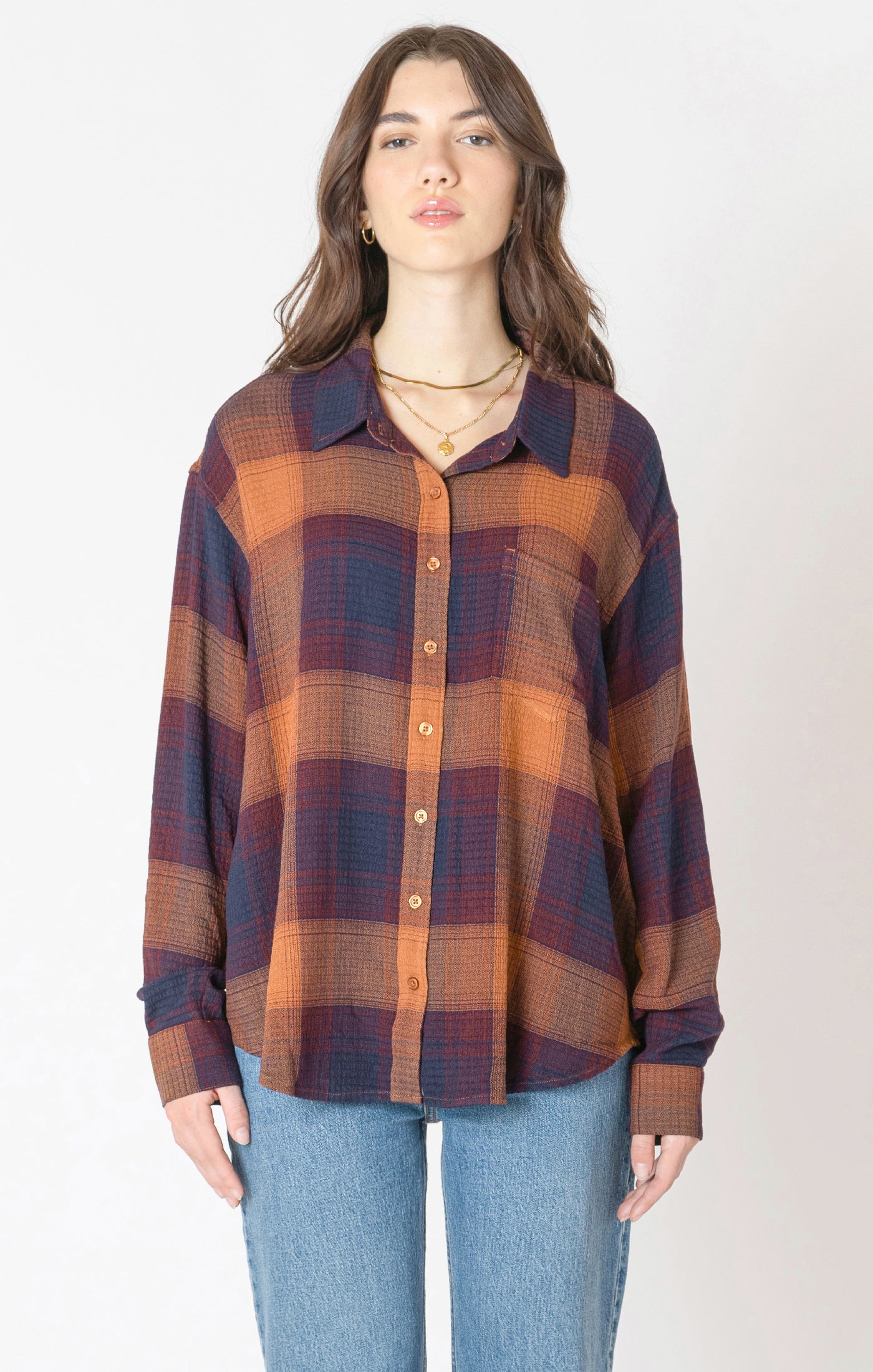 A flannel style button up shirt, with orange, blue, and red autumnal colors. 