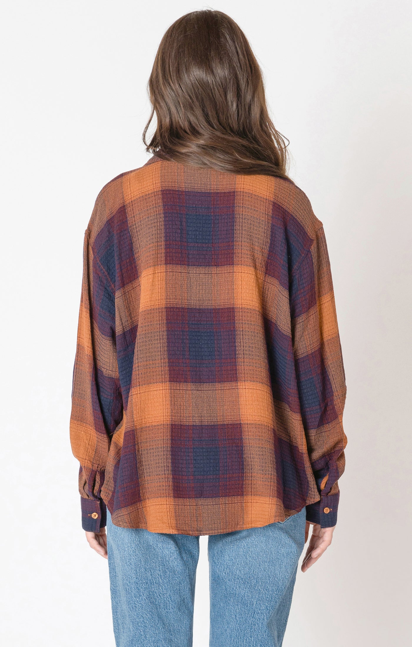 A flannel style button up shirt, with orange, blue, and red autumnal colors. 