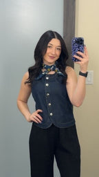 A person taking a mirror selfie wearing a denim outfit and a neck scarf.