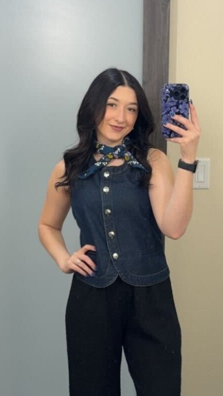 A person taking a mirror selfie wearing a denim outfit and a neck scarf.