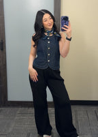 A woman taking a mirror selfie wearing a dark denim top with black pants.