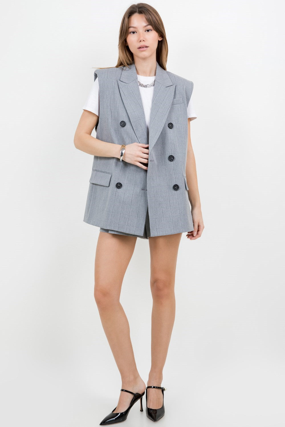 A grey suit jacket style vest, with double-breast buttons, slightly padded shoulders, and pinstripe details.