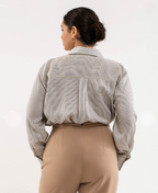 Person wearing a striped shirt and beige pants on a white background