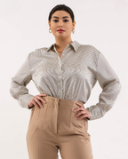 Woman wearing a patterned shirt and beige pants on a white background