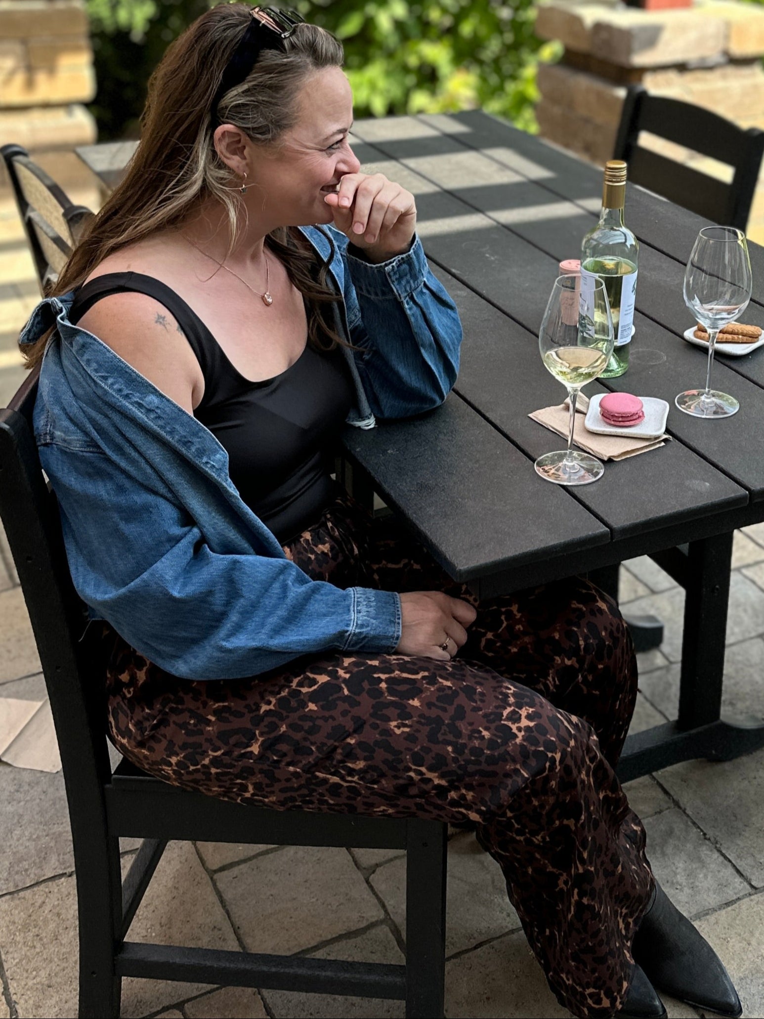 Woman sitting at an outdoor table with drinks on a patio
