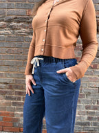 Light brown cardigan with drawstring pants on a woman in front of a brick wall