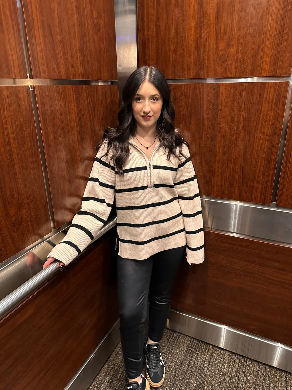 A cozy cream sweater with horizontal black stripes, and a half zipper, and a collar.