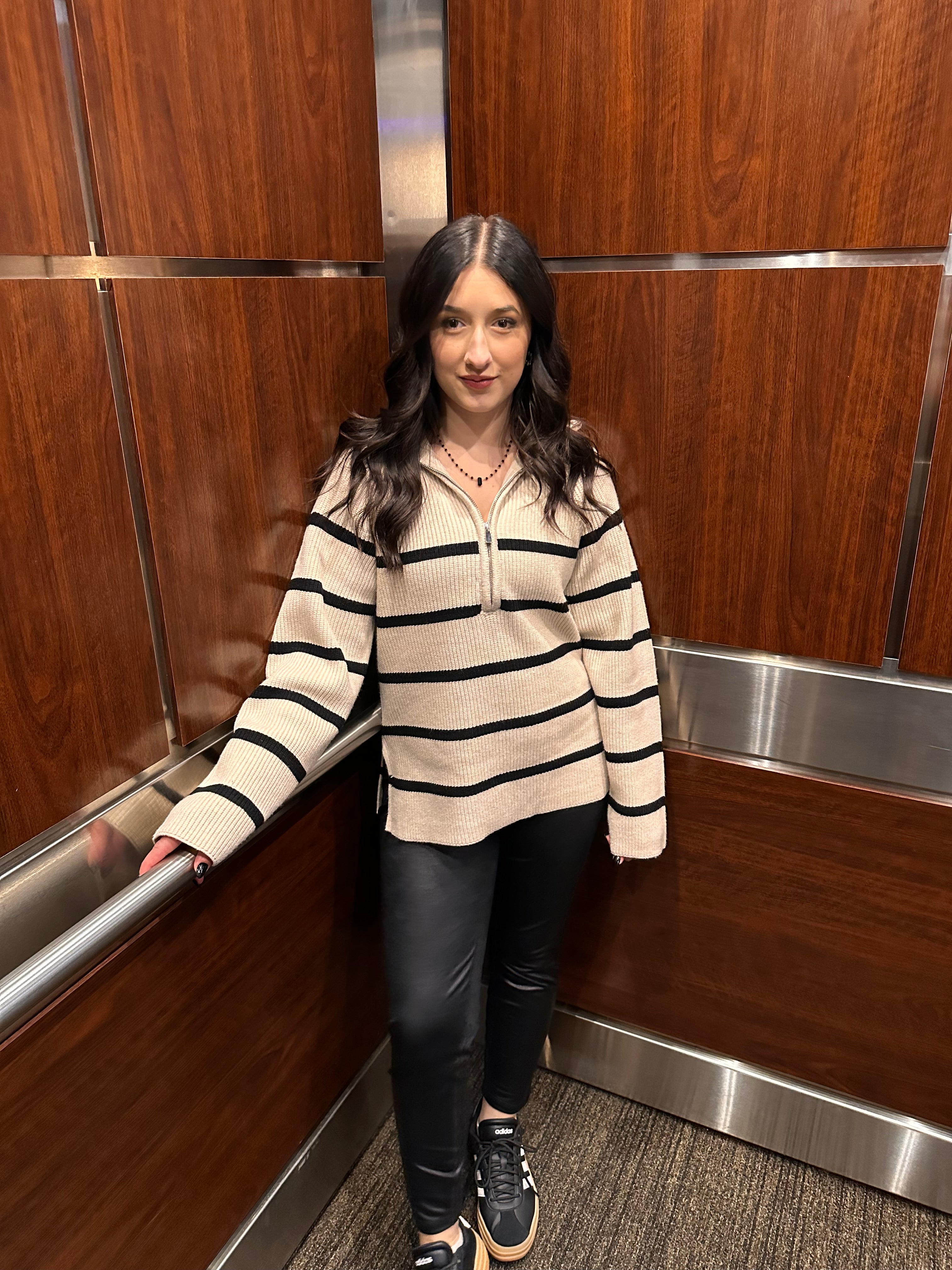 A cozy cream sweater with horizontal black stripes, and a half zipper, and a collar.