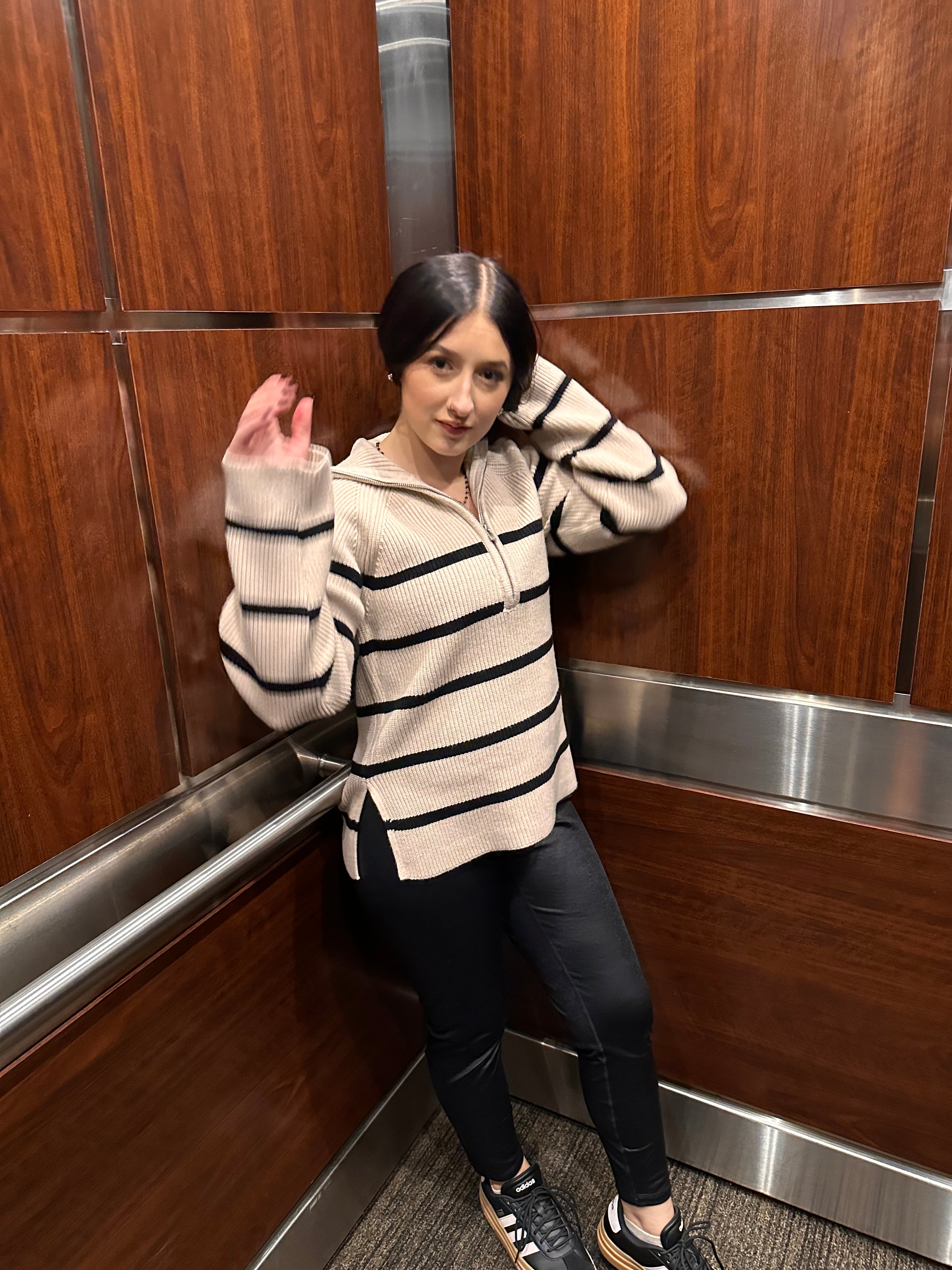 A cozy cream sweater with horizontal black stripes, and a half zipper, and a collar.