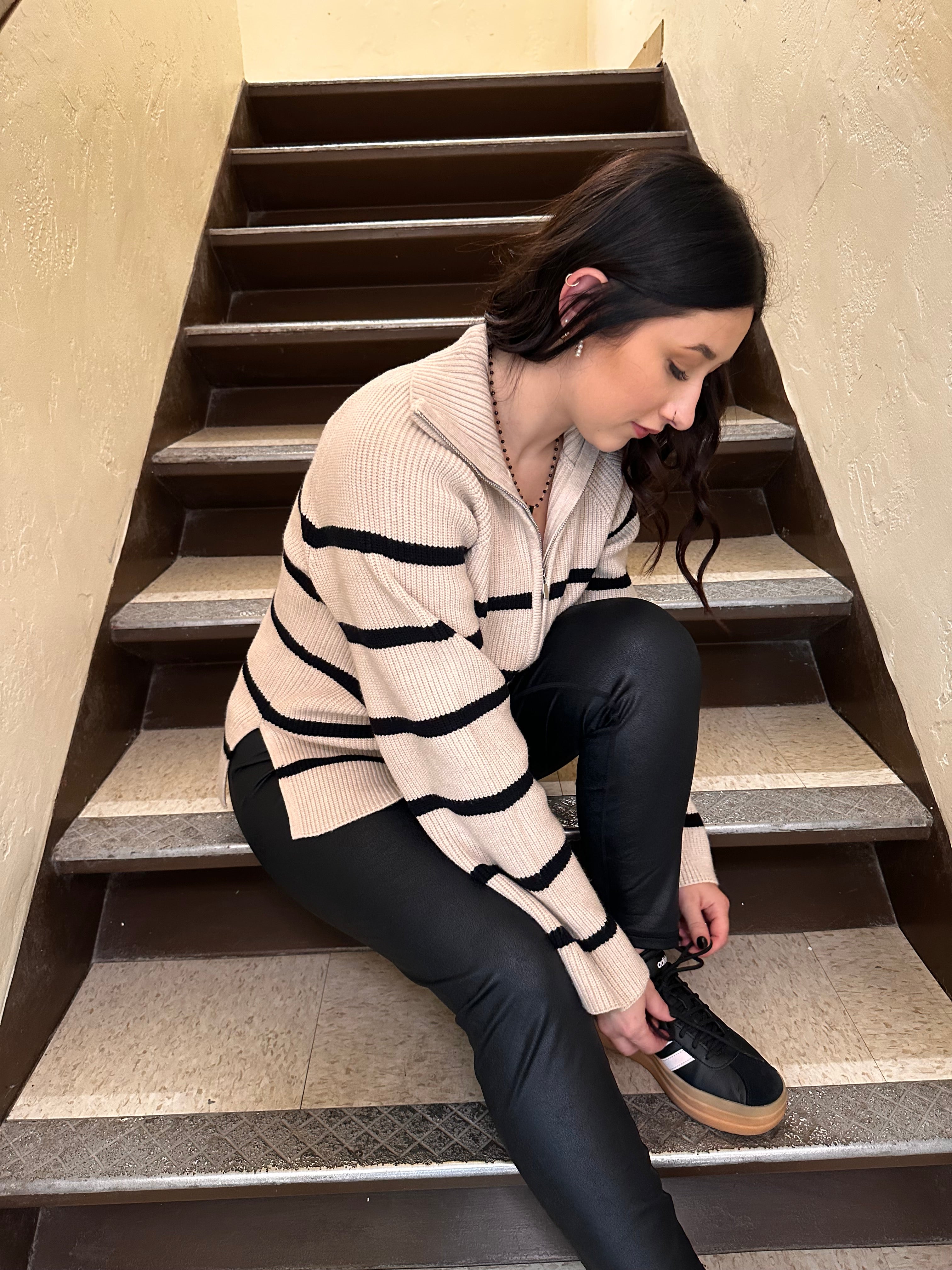 A cozy cream sweater with horizontal black stripes, and a half zipper, and a collar.