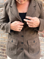 A woman in a brown tweed coat with button details.