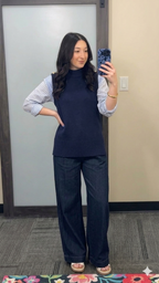 Woman taking a mirror selfie wearing a navy sweater, checkered shirt, and wide-leg pants.
