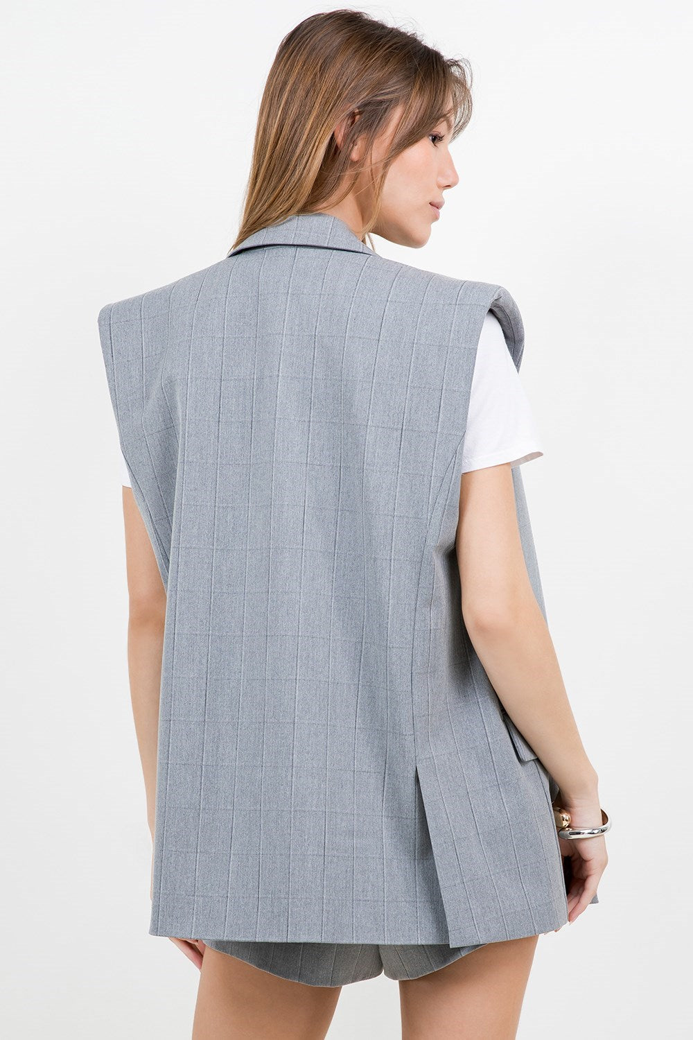A grey suit jacket style vest, with double-breast buttons, slightly padded shoulders, and pinstripe details.