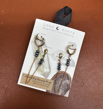 Gold earrings for a double pierced ear, with one hoop connected to a post earring with a chain between the two with small stones.