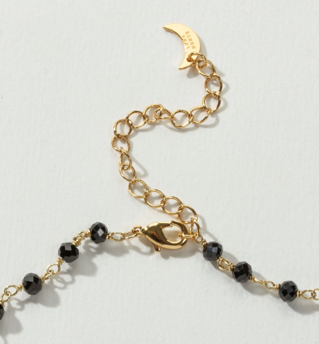 Gold chain necklace with black beads and a lobster clasp.