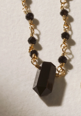 Necklace with black beads and gold chain with an onyx point center stone
