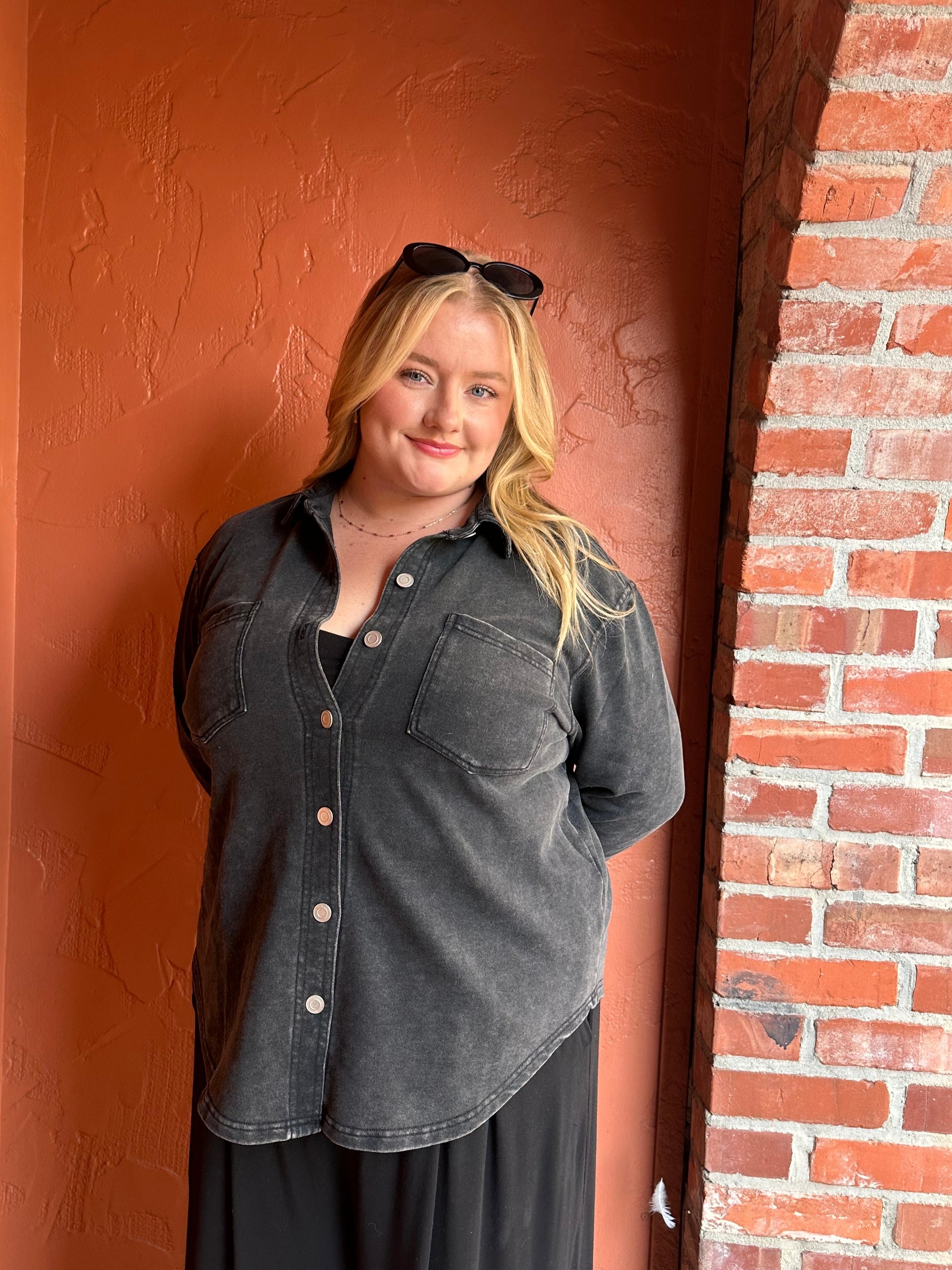 Person wearing a dark coat against a brick wall.
