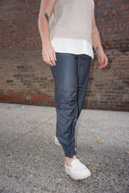A sharp pair of trousers, in a dark blue pinstripe material, with a button on the hem, allowing you to choose how to style these pants.