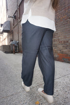 A sharp pair of trousers, in a dark blue pinstripe material, with a button on the hem, allowing you to choose how to style these pants.