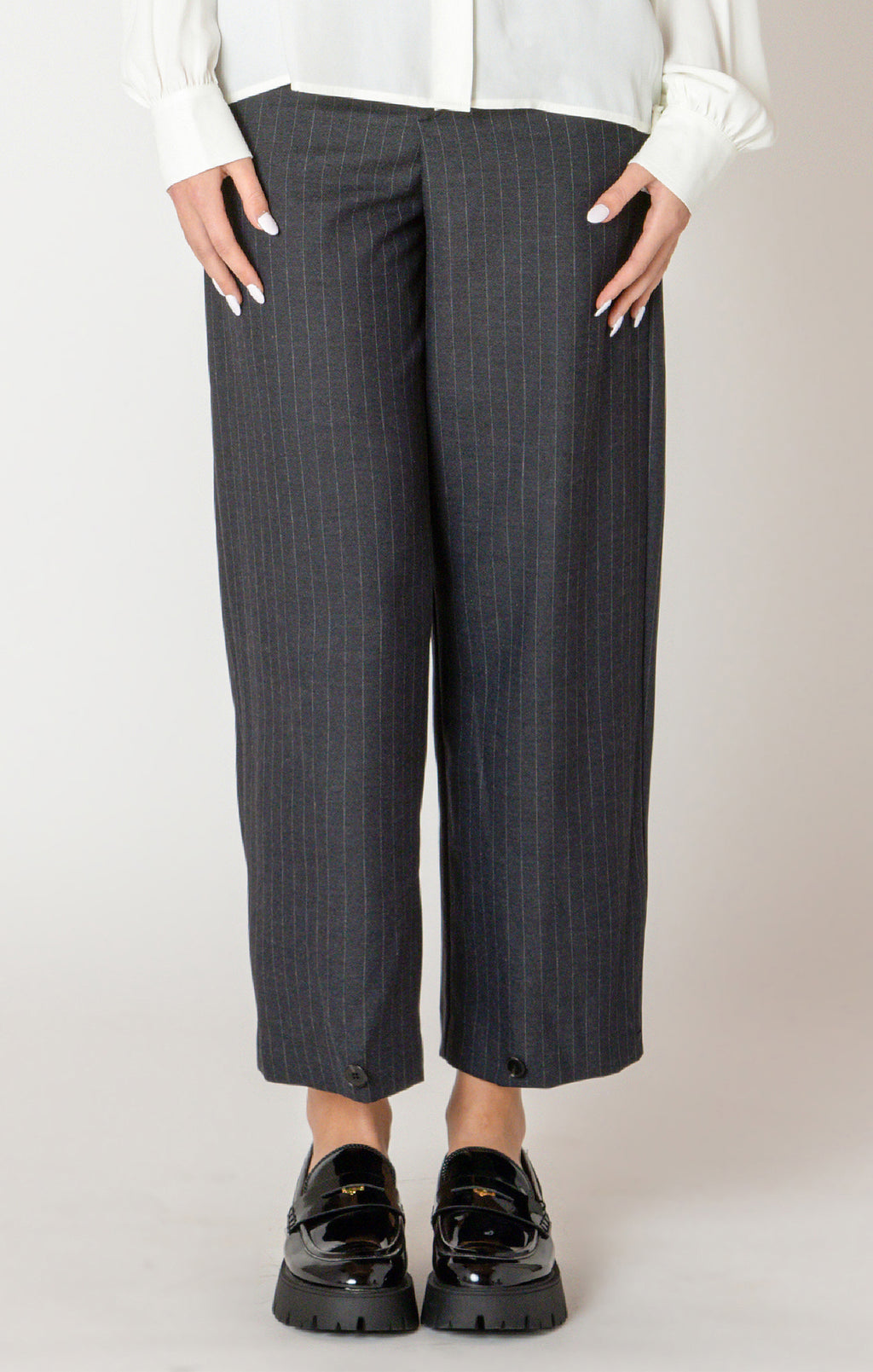 A sharp pair of trousers, in a dark blue pinstripe material, with a button on the hem, allowing you to choose how to style these pants.