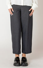 A sharp pair of trousers, in a dark blue pinstripe material, with a button on the hem, allowing you to choose how to style these pants.