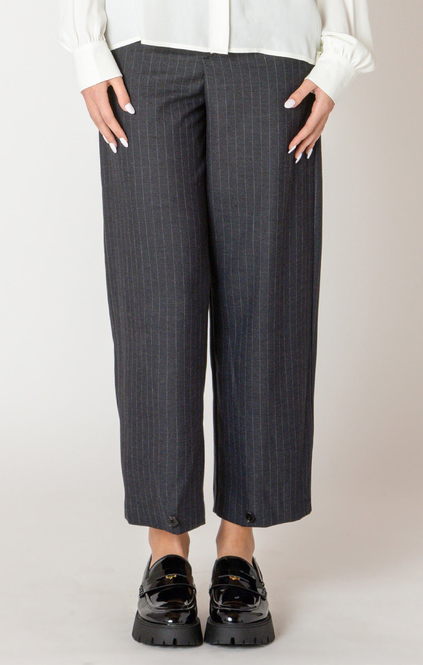 A sharp pair of trousers, in a dark blue pinstripe material, with a button on the hem, allowing you to choose how to style these pants.