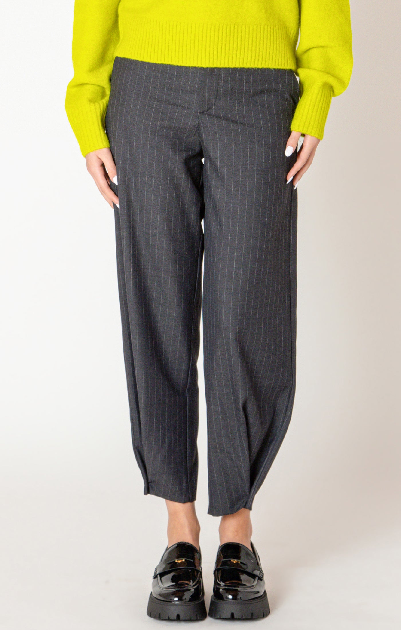 A sharp pair of trousers, in a dark blue pinstripe material, with a button on the hem, allowing you to choose how to style these pants.