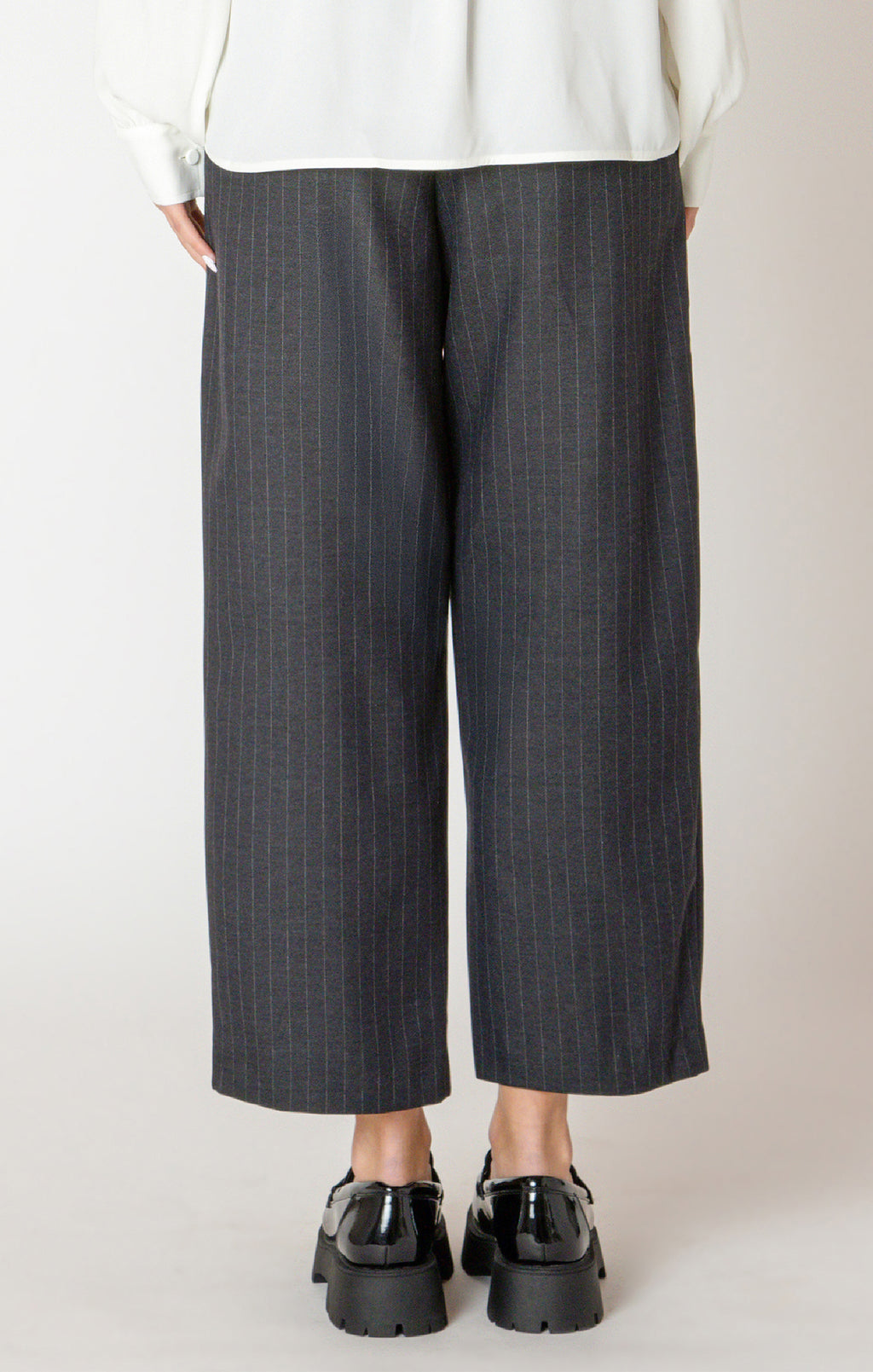 A sharp pair of trousers, in a dark blue pinstripe material, with a button on the hem, allowing you to choose how to style these pants.