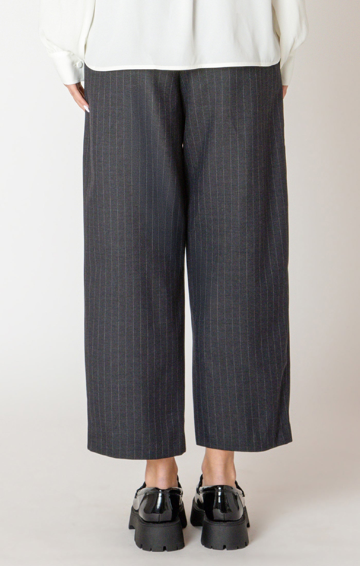 A sharp pair of trousers, in a dark blue pinstripe material, with a button on the hem, allowing you to choose how to style these pants.