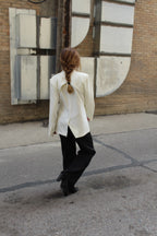 A white suite jacket with a shoulder blade vent detail.