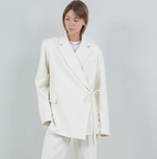 Person wearing a white wrap front blazer and pants on a plain background