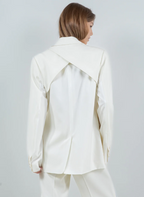 Woman wearing a cream and white blazer with a cross over detail in the back.