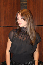 A chic black blouse, with a see-through material, high neck line, cap sleeves, and a gathered waist.