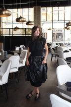 A chiq black sheer top with a gathered waist, mock neck, and cap sleeves.