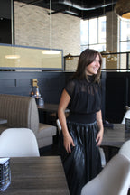 A black sheer top with a mock neck, cap sleeves, and a gathered waist.