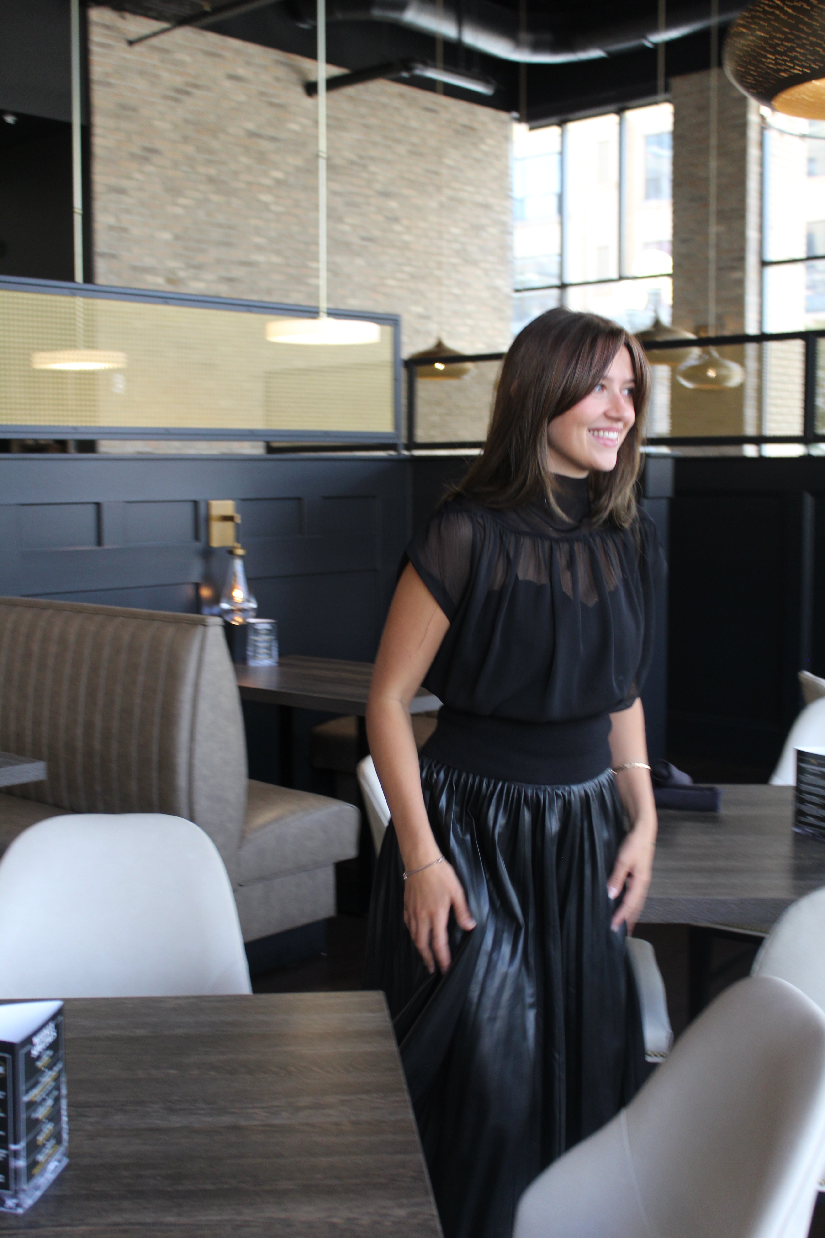 A black sheer top with a mock neck, cap sleeves, and a gathered waist.
