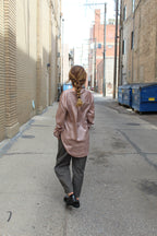 Person wearing a rose vertical striped button down that has reflective and glossy texture and covers her bottom.