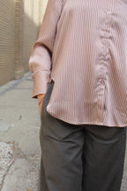 Person wearing a striped shirt and dark pants on a concrete floor.