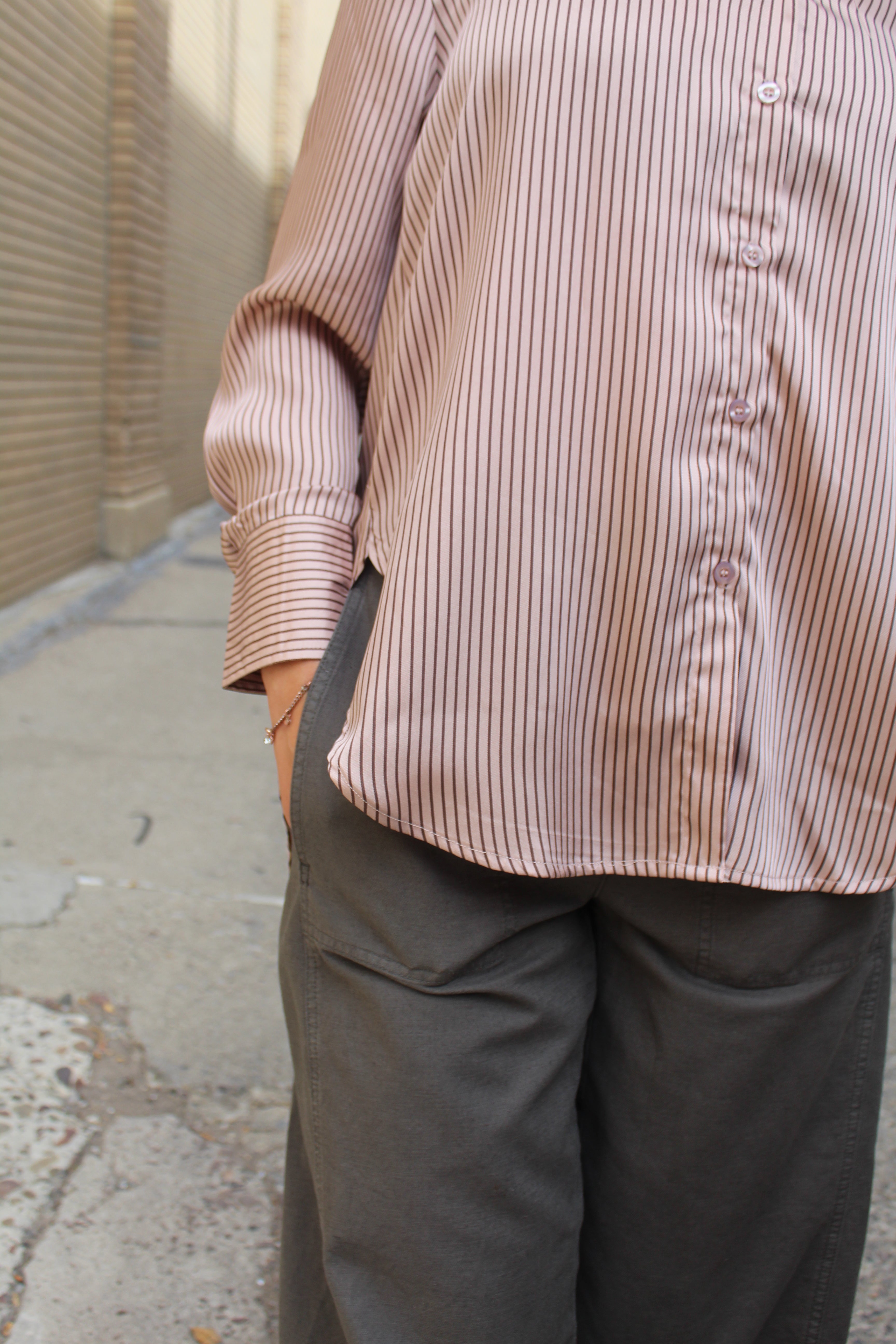 Person wearing a striped shirt and dark pants on a concrete floor.