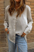 Person wearing a striped shirt and jeans against a brick wall