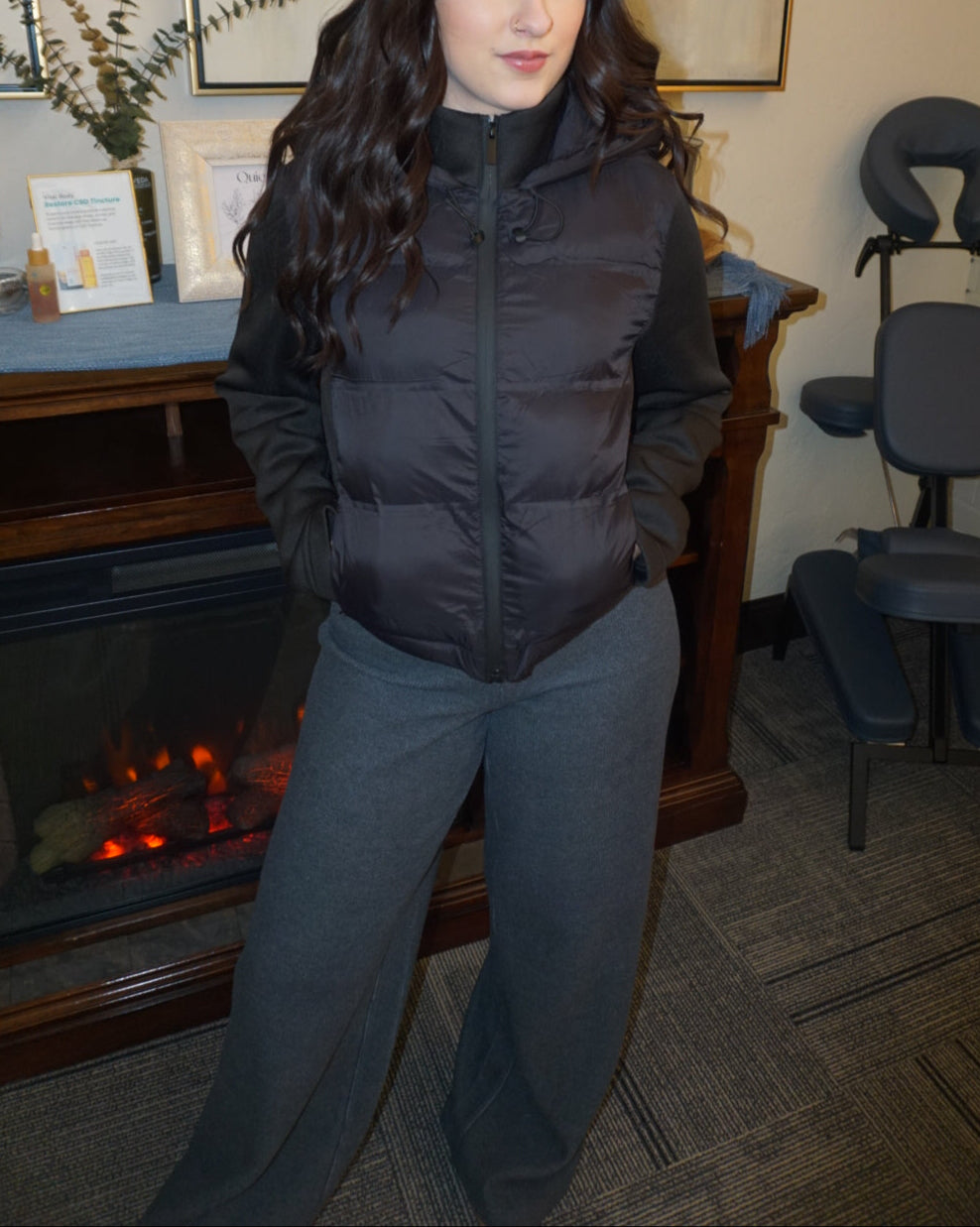 A black puffer jacket with a hood, and thick, stretchy, knitted sleeves.