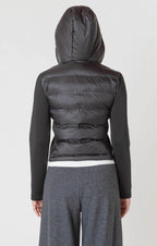 A black puffer jacket with a hood, and thick, stretchy, knitted sleeves.