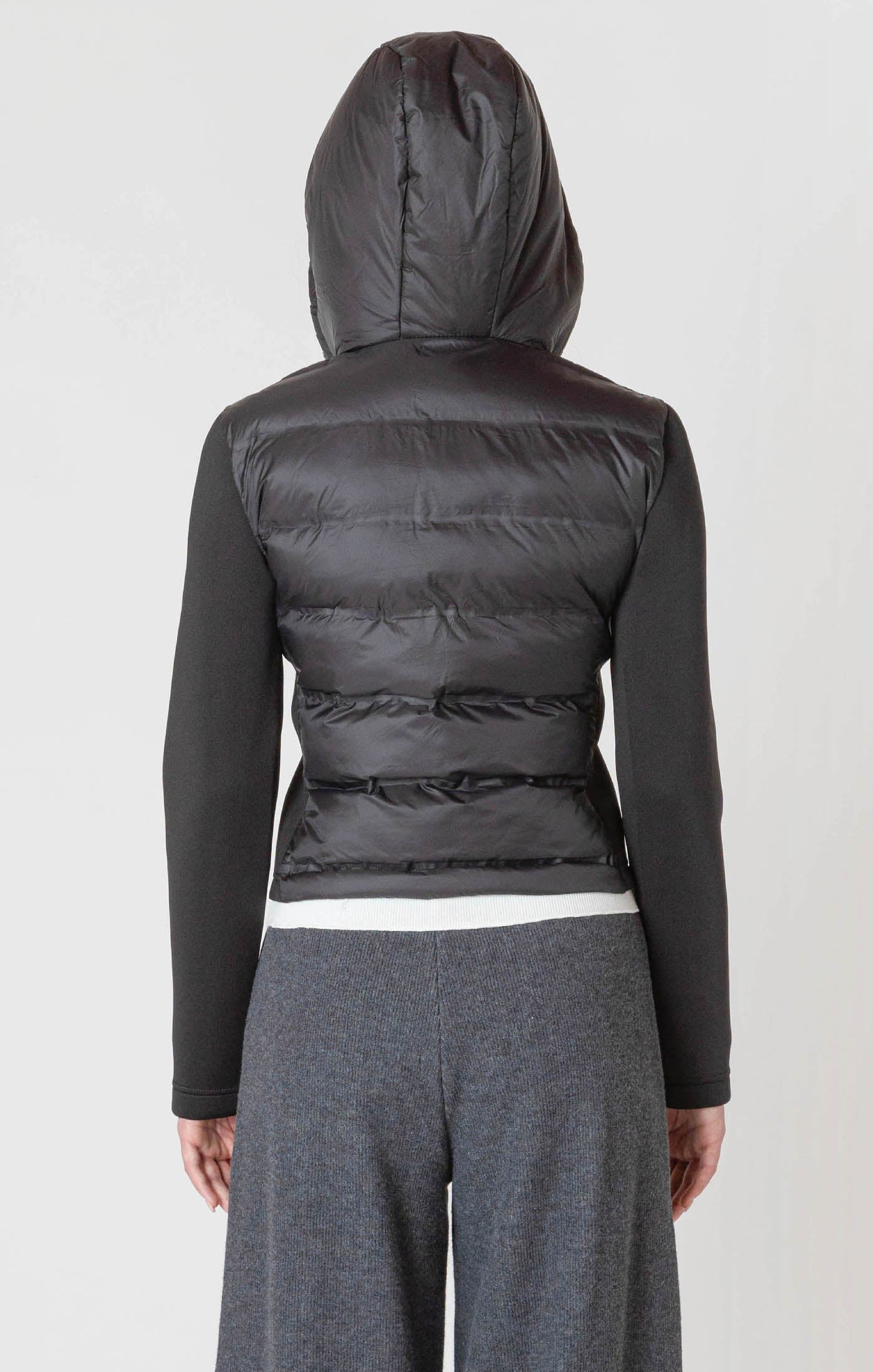 A black puffer jacket with a hood, and thick, stretchy, knitted sleeves.